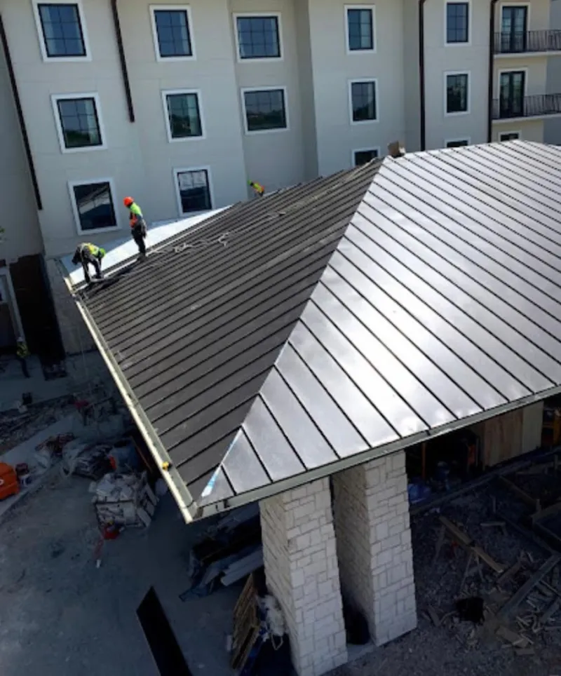 Crew installing standing seam metal roof panels on a commercial project in Commerce City